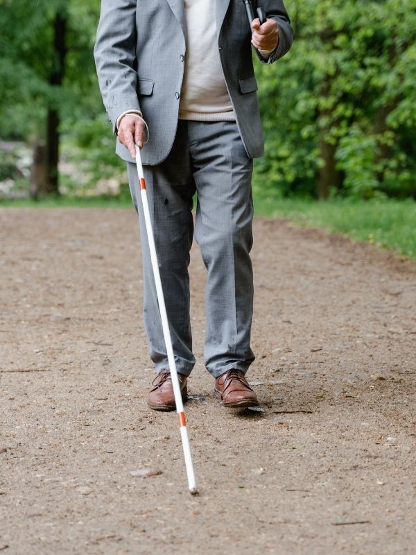 Resimde toprak zeminde bastonu ile yürüyen birisi mevcut